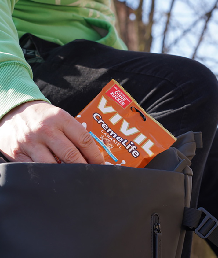 Bonbontüte Caramel wird aus dunklem Rucksack gezogen