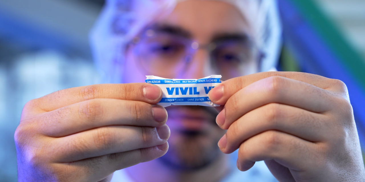 Ein blaues VIVIL-Bonbon wird von einer Person in die Kamera gehalten